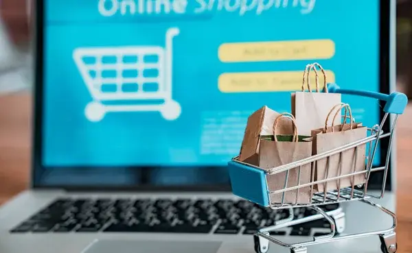 carrito de compras frente a una computadora representando el impacto de un ecommerce
